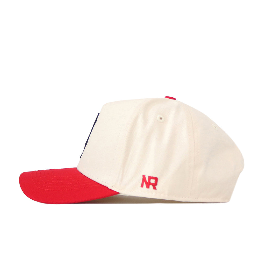 A white Wisconsin Patch Hat by No Rivals, featuring a red brim and a red button on top, is shown from the side. Red embroidered NR initials near the back add a distinctive touch to this officially licensed cap.