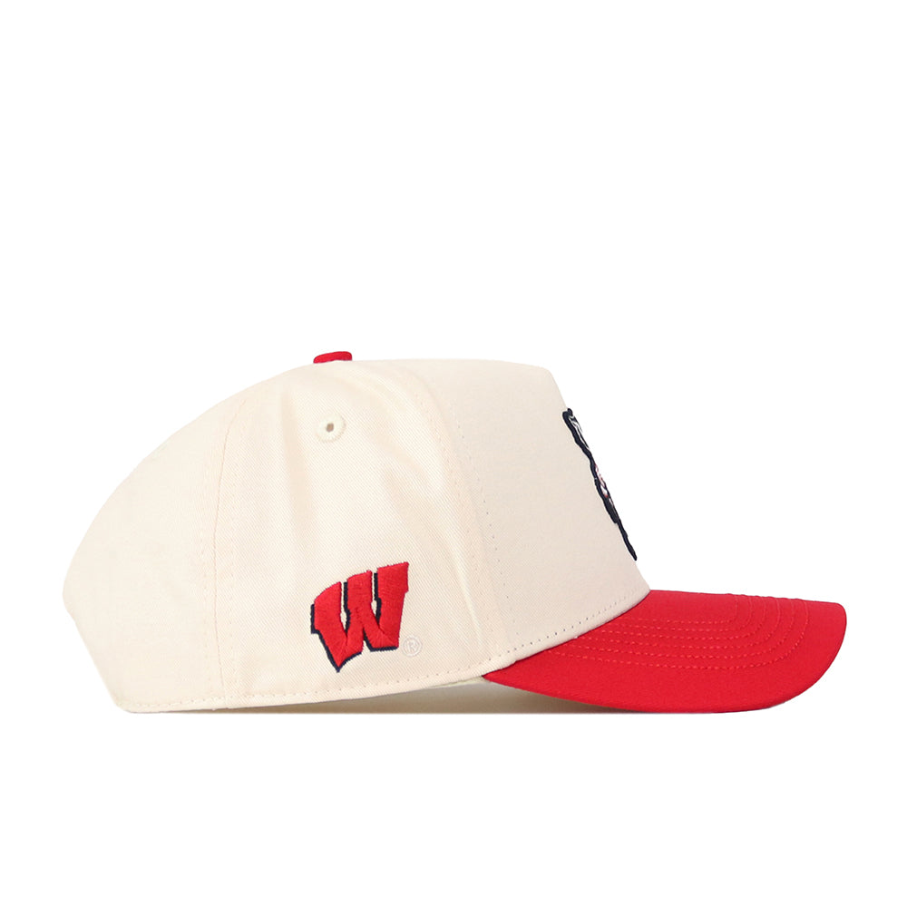 The Wisconsin Patch Hat by No Rivals is a cream-colored snapback with a bold red brim and embroidered logos, including a red “W” logo on the side. This officially licensed baseball cap is displayed in a left-facing side view against a white background.
