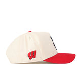 The Wisconsin Patch Hat by No Rivals is a cream-colored snapback with a bold red brim and embroidered logos, including a red “W” logo on the side. This officially licensed baseball cap is displayed in a left-facing side view against a white background.