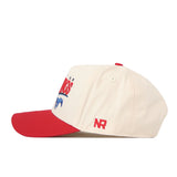 The No Rivals SMU Mustangs Stride Hat is a cream snapback baseball cap featuring a red brim. The side displays red embroidered “NR” initials, while the front showcases officially licensed SMU Mustangs graphics and text in red and blue, partially visible from this angle. Detailed embroidered logos complete the authentic look.