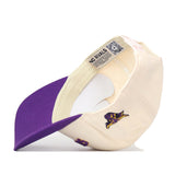 The Minnesota State Mavericks | Upside Down Mavericks Hat - Classic by No Rivals is pictured here in cream and purple, displayed upside down. The underside of the brim is purple, and a small embroidered logo of a purple and yellow animal—representing the Minnesota State Mavericks—adorns the side. Inside, a label reading NO RIVALS emphasizes this snapback’s distinctive flair.