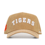 The Clemson Rustic Hat by No Rivals is a tan snapback cap with "TIGERS" in white on the front, an orange paw print on the left side, durable cotton canvas construction, and is officially licensed.