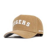 The Clemson Rustic Hat by No Rivals is a tan cotton canvas cap with TIGERS in white raised letters on front and NO RIV on the side. It features a structured fit, curved brim, and adjustable strap for comfort.