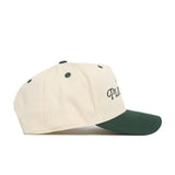 The No Rivals Play Golf Hat - Classic Green features a cream-colored snapback design, dark green brim, green eyelets, and partially visible black embroidered logo text on the front panel. Shown from the side.