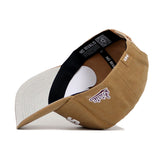 A brown and beige cotton canvas baseball cap by No Rivals, the Mississippi State Rustic Hat, shown upside down with a black sweatband, light beige brim, snapback closure, inside labels, and "Rivals" embroidered in purple near the side.