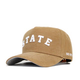 The Mississippi State Rustic Hat by No Rivals is a tan cotton canvas baseball cap with bold white "STATE" on the front, "NO RIV" on the brim, visible stitching, curved bill, and snapback closure for adjustable fit.