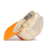 The Tennessee Starter Hat by No Rivals is shown upside down to reveal the inside label with the brand name and the orange underside of the cream-colored brim. This officially licensed snapback cap also features an embroidered logo for a stylish finishing touch.