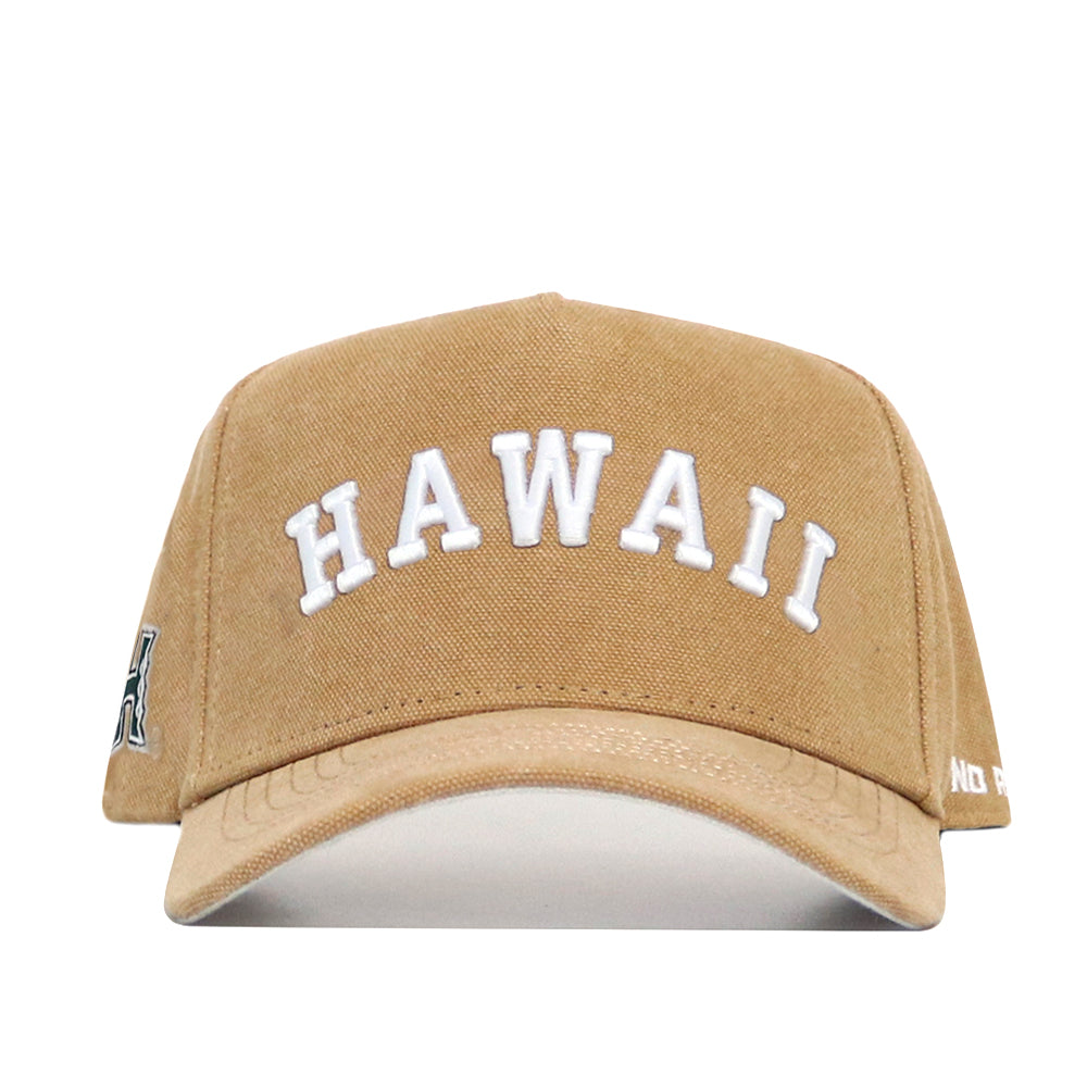 The No Rivals Hawaii Rustic Hat is a tan cotton canvas cap with "HAWAII" embroidered in white on the front, viewed from a front-facing angle.