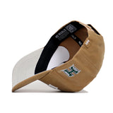 The Hawaii Rustic Hat by No Rivals is a tan cotton canvas snapback with a white brim, side view shown. It features a green and white stylized H logo and an inside label reading NO RIVALS. Officially licensed.