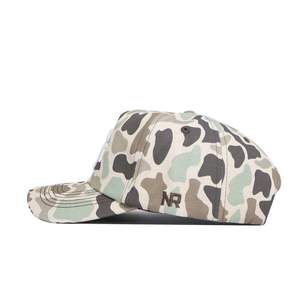 A side view of the No Rivals Texas A&M Huntsman Hat shows its 5-panel green, beige, and brown camo pattern. "NR" is embroidered in dark brown above the brim on the side. It features a classic snapback for adjustable fit.