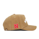 The Nebraska Rustic Hat by No Rivals is a tan cotton canvas snapback cap with a red and white N logo on the side, partially visible white embroidered front text, and a small NR tag by the brim.