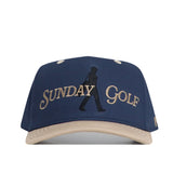 The No Rivals Sunday Golf Hat in navy and tan is a high-quality cotton snapback with "SUNDAY GOLF" in gold and an embroidered walking silhouette between the words.
