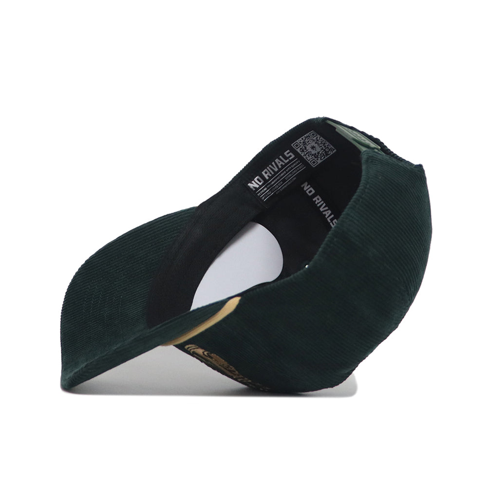 The Saturday Scramble Cord Hat - Green by No Rivals is shown from the inside, lying on its side with the brim facing forward. Its snapback closure and inner band featuring NO RIVALS in white complete the unique look.