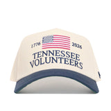 The No Rivals Tennessee Vols 250th Americana Hat is a white snapback with a navy brim, embroidered American flag, "1776," "2026," and "Tennessee Volunteers"—the perfect Gameday fit.