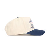 The No Rivals Tennessee Vols 250th Americana Hat is a beige snapback cap with a navy brim, side view shown. It features an embroidered logo, text, a small American flag, and “1776” above the flag—ideal for your next Gameday Fit.