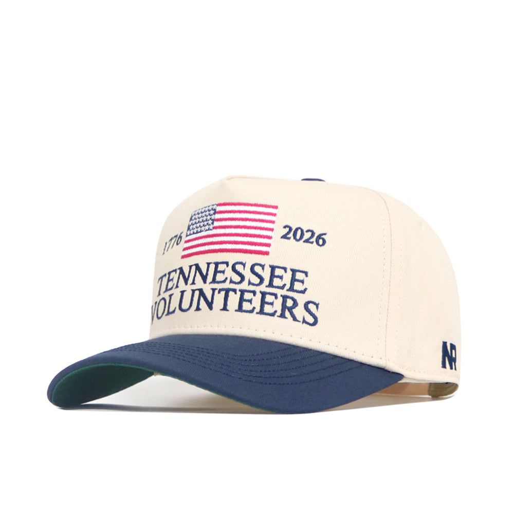 The No Rivals Tennessee Vols 250th Americana Hat is a beige cap with a blue brim, embroidered American flag, "1776" and "2026," plus "Tennessee Volunteers" in blue—perfect for showing your spirit on gameday.