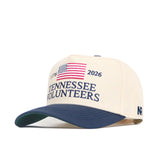 The No Rivals Tennessee Vols 250th Americana Hat is a beige cap with a blue brim, embroidered American flag, "1776" and "2026," plus "Tennessee Volunteers" in blue—perfect for showing your spirit on gameday.