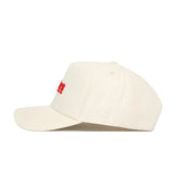 The Nebraska Sideline Hat by No Rivals features a cream snapback design with red embroidered front text and a white NR monogram on the side, crafted from premium cotton for a structured fit.