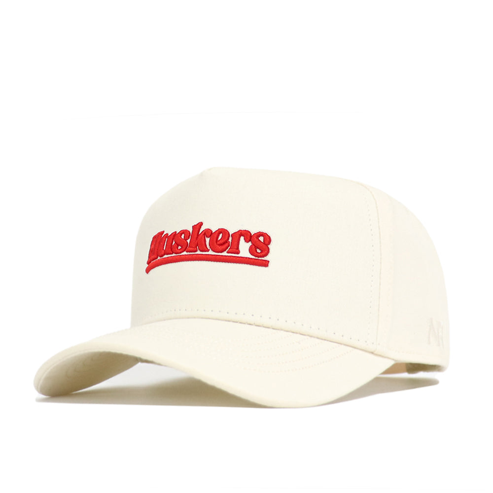 The Nebraska Sideline Hat by No Rivals is a cream snapback with "Huskers" boldly embroidered in red, featuring a curved brim and structured crown for a comfortable, classic style.