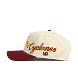 The Iowa State Halftime Hat by No Rivals is a premium cream cotton snapback with a maroon brim, "Cyclones" embroidered in gold script, and maroon NR lettering on the side.