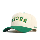 The Upside Down Ducks Hat - Oregon - Classic by No Rivals is a cream snapback with green accents and brim, "DUCKS" embroidered upside down in green and yellow on the front, and "NO RIV" stitched on the side above the adjustable strap.