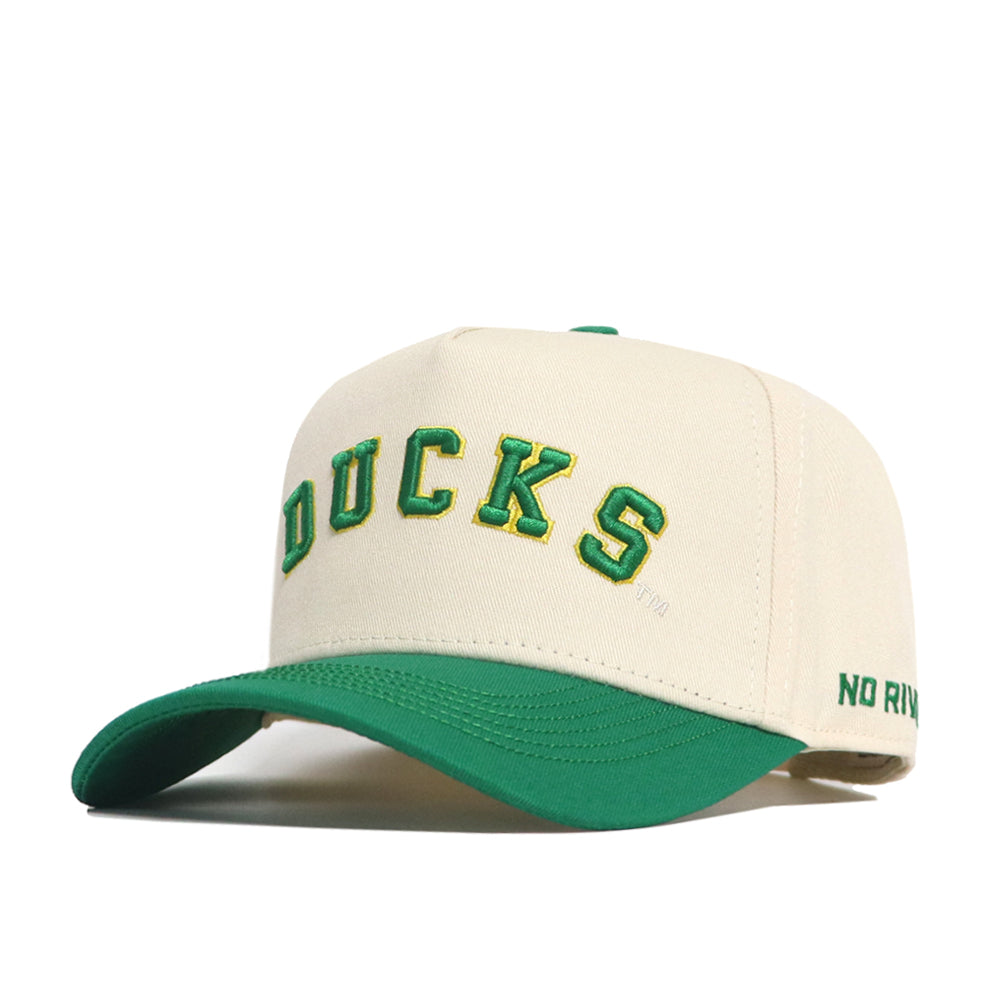 The Right Side Up Ducks Hat - Oregon - Classic by No Rivals features a cream color, green brim, "DUCKS" embroidered in green and yellow on the front, snap back closure, and "NO RIVAL" stitched in green on the side of the brim.