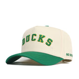 The Right Side Up Ducks Hat - Oregon - Classic by No Rivals features a cream color, green brim, "DUCKS" embroidered in green and yellow on the front, snap back closure, and "NO RIVAL" stitched in green on the side of the brim.