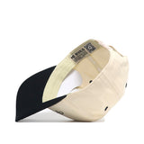 The Play Golf Hat - Teed Up - Classic Black by No Rivals is shown upside down, revealing inside labels, stitching, ventilation eyelets, a snapback closure, and an officially licensed embroidered logo.