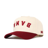 The Upside Down BAMA Hat - Alabama - Classic by No Rivals features a cream snapback with a red brim, red upside down BAMA embroidery on the front, NR stitched in red on the side, and is made from high-quality cotton for comfort and style.