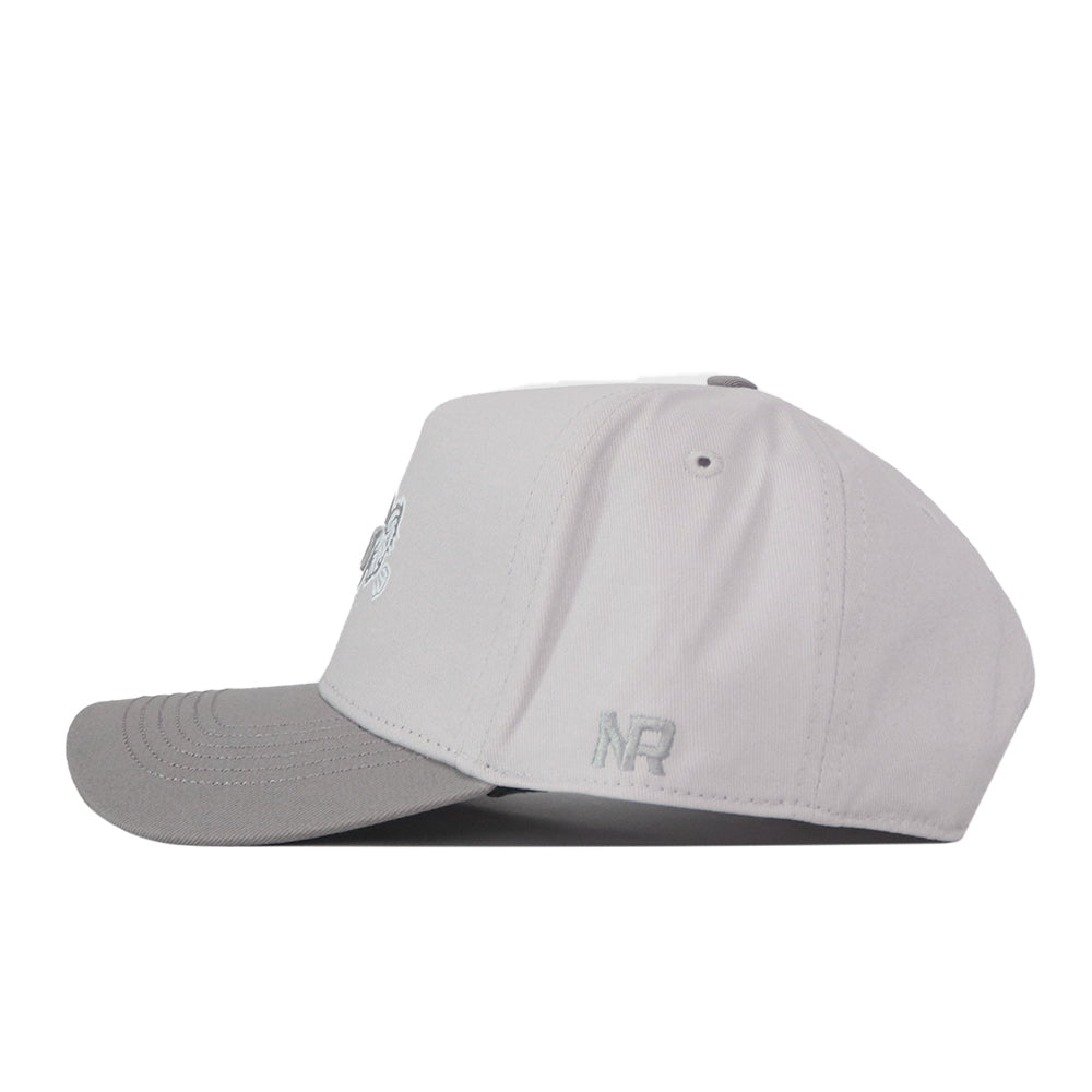 A side view of the No Rivals NDSU Graphite Hat shows its light gray snapback design with a darker gray curved brim, stitched eyelets, and an embroidered NR logo near the edge—perfect for elevating your gameday fit.