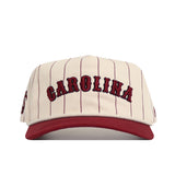 The No Rivals South Carolina Walk Off Hat features a cream cotton fabric with thin maroon pinstripes, bold maroon "CAROLINA" embroidery on the front, a maroon brim, and an unstructured fit for relaxed comfort.