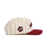 The No Rivals South Carolina Walk Off Hat is a cream cotton cap with thin maroon pinstripes, an unstructured fit, a solid maroon brim, and a maroon SC logo embroidered on the side.