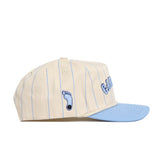 The No Rivals North Carolina Walk Off Hat features a cream snapback design with blue pinstripes, a blue brim, and an embroidered blue footprint logo. Made from high-quality cotton and offering an unstructured fit for comfort and style.
