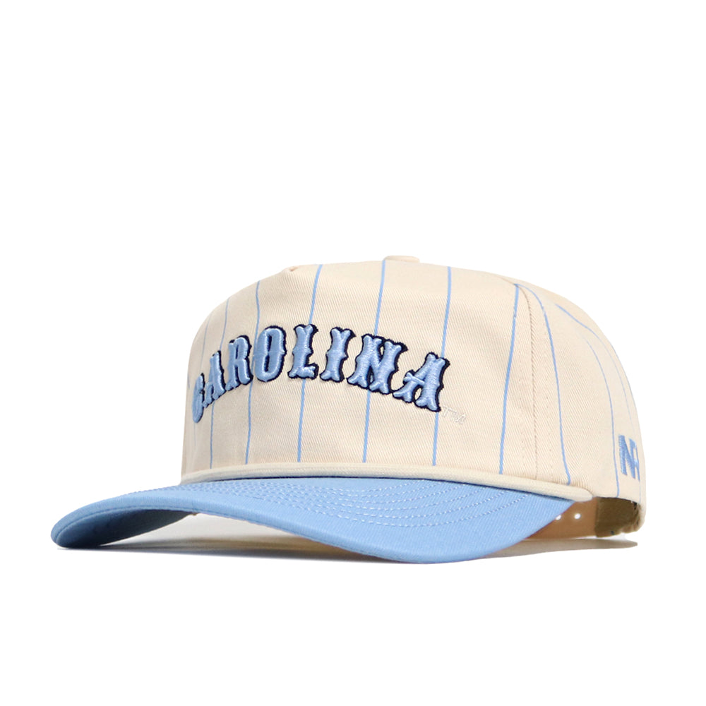 The No Rivals North Carolina Walk Off Hat is a beige cotton baseball cap with thin blue pinstripes, large CAROLINA embroidery, a light blue brim, an unstructured fit, and a small blue N logo on the side.