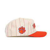 The No Rivals Clemson Walk Off Hat is a cream cotton baseball cap with red pinstripes, an orange brim, and an orange paw print logo on the side. Its unstructured fit offers a relaxed, casual style.
