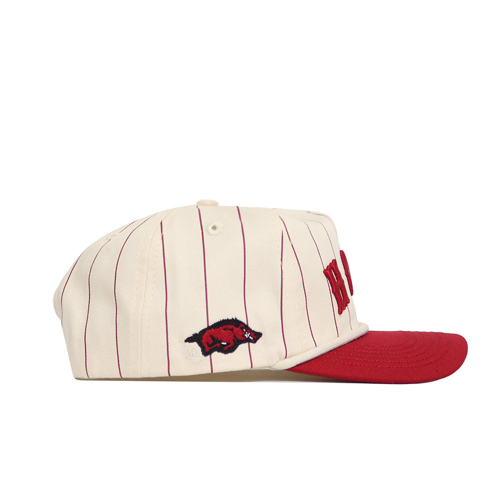 The No Rivals Arkansas Walk Off Hat is a cream cotton adjustable cap with thin red vertical stripes, a red brim, and an embroidered red Razorback logo on the side.