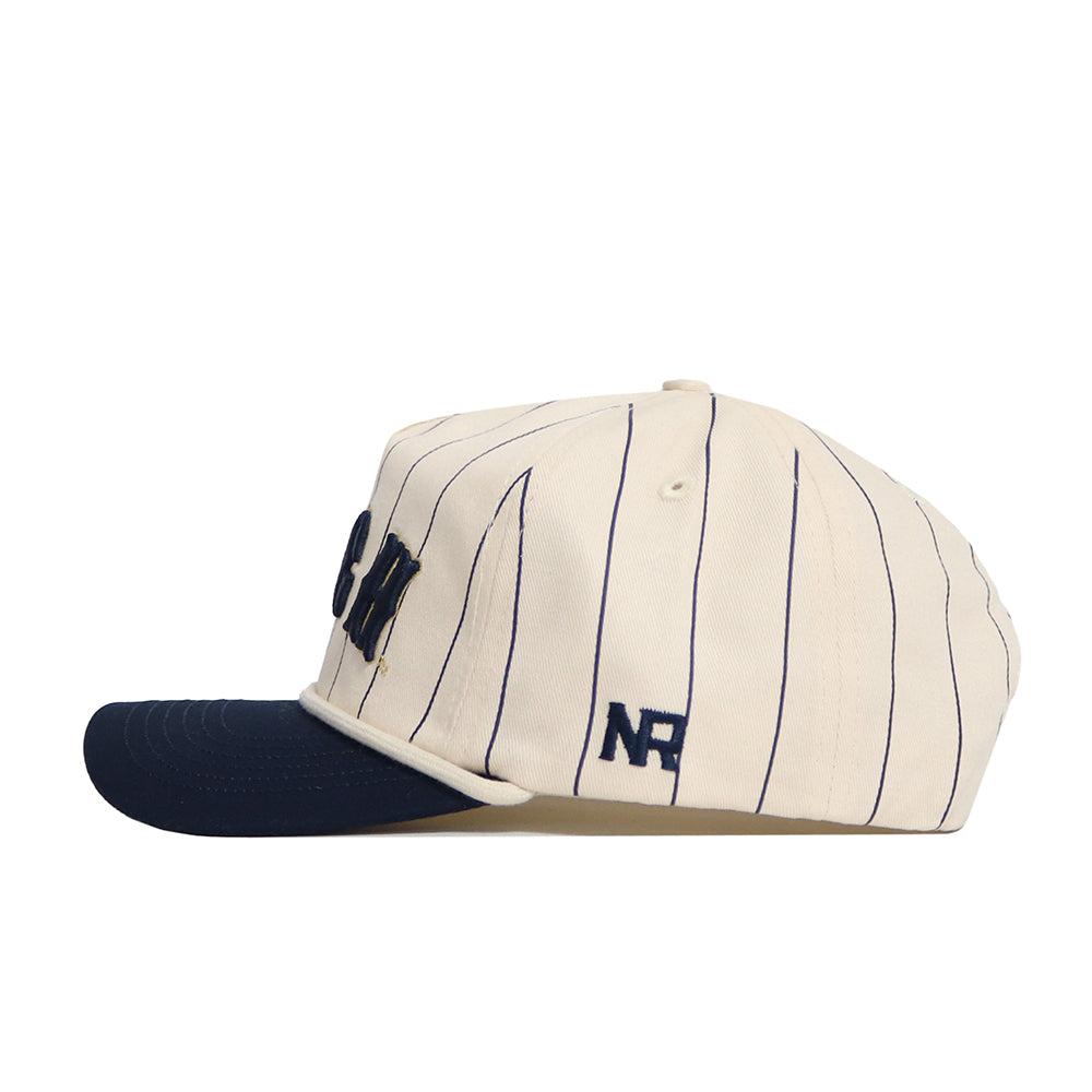 The No Rivals Georgia Tech Walk Off Hat features a cream color with thin navy pinstripes, a navy brim, and navy embroidered NR letters on the side. Made from high-quality cotton for comfort and style.