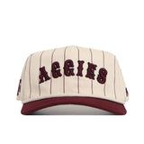The No Rivals Texas A&M Walk Off Hat is a cream snapback with thin maroon stripes, bold AGGIES lettering, a maroon brim, high-quality cotton fabric, and an unstructured fit for comfort.