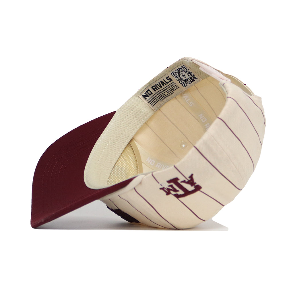 The Texas A&M Walk Off Hat by No Rivals is a cream-colored unstructured snap back with thin maroon stripes, maroon brim, an A and T logo on the side, and NO RIVALS text on the inner band. The hat is shown positioned on its side.