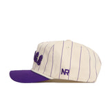 The TCU Walk Off Hat by No Rivals features a cream base with thin purple stripes, a purple brim, and embroidered NR on the side. Made from durable cotton, this snapback delivers both comfort and style.