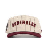 The Florida State Walk Off Hat by No Rivals is a cream snapback with thin maroon stripes, SEMINOLES embroidered in maroon on the front, a maroon brim, soft cotton fabric, and a small logo patch on the left side.