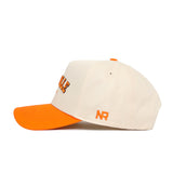 The Knoxville Hometown Hat by No Rivals is a cream cotton baseball cap with an orange brim and button, featuring an embroidered NR on the side and partial orange lettering on the front.