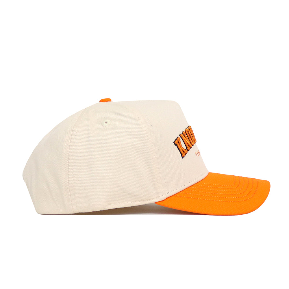 The No Rivals Knoxville Hometown Hat is a cream snapback with an orange brim and top button, made from premium cotton. It features front embroidered text and a structured fit, shown in a side view.
