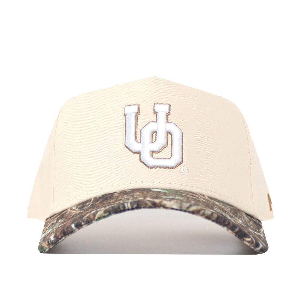 The No Rivals Oregon Camo Connector Hat features a beige snapback design, white "UD" embroidery on the front, and a camouflage-patterned brim—perfect for your gameday look.