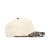 The Oregon Camo Connector Hat by No Rivals is a beige snapback with a curved brim, green and brown camo pattern, perfect for gameday style. Shown from the side against a white background.