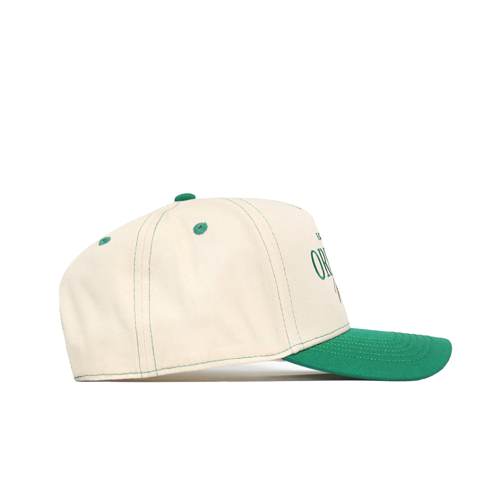 The No Rivals Oregon Vintage Hat is a cream-colored baseball cap with a green brim, top button, stitching, and eyelets. Shown in side view, it features an embroidered logo for an officially licensed look.