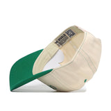 The Oregon Vintage Hat by No Rivals is displayed upside down, revealing its cream color, green brim, detailed interior stitching, embroidered “NO RIVALS” logo, and snapback adjustment.