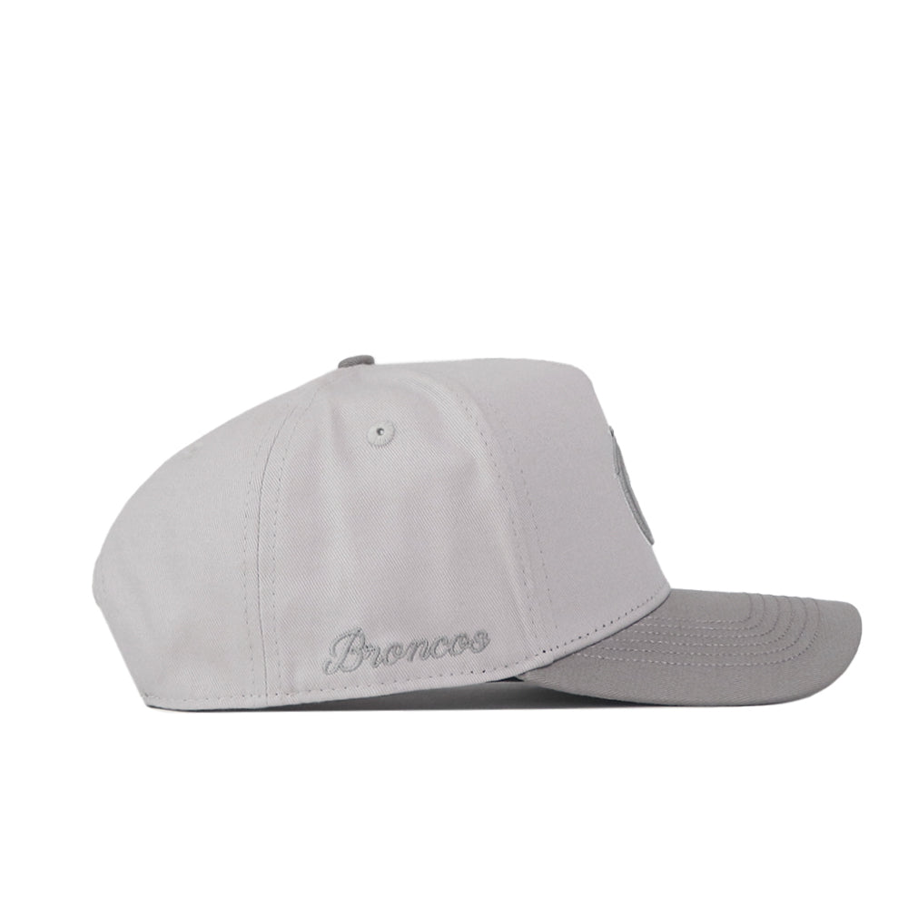 A Boise State Graphite Hat by No Rivals, featuring light gray fabric and “Broncos” embroidered on the side in matching thread, is displayed in a side profile against a plain white background. Ideal for finishing off your gameday look.