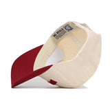 The Bloomington Hometown Hat by No Rivals is shown upside down, revealing its cream cotton body, red brim, inner lining, stitching, and a fabric label that reads NO RIVALS.