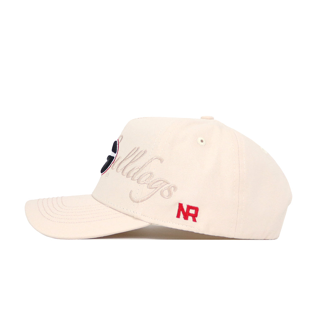 The No Rivals Georgia Stacked Hat is a beige cotton cap with a structured fit, Bulldogs embroidered in cursive on the side, a red NR logo near the brim, eyelets on top, and a curved bill.